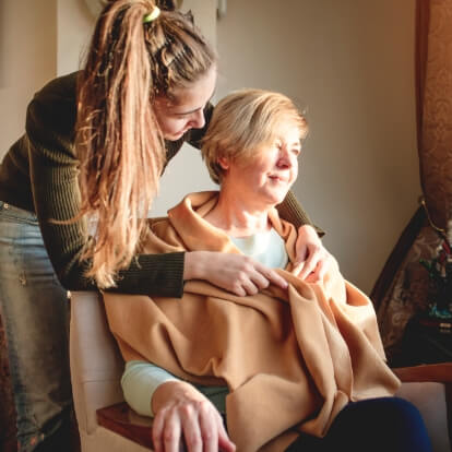 Woman putting a blanket on an elderly person in a wheelchair