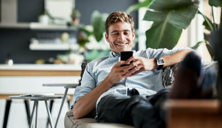 Man laying on couch looking at cellphone